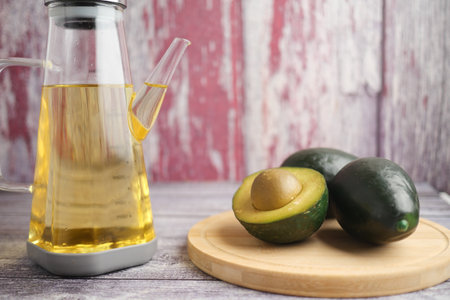 Fresh avocado and oil on wooden cutting board in kitchenの写真素材