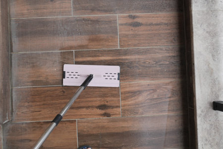 Cleaning a wooden floor with a mop in a bright room