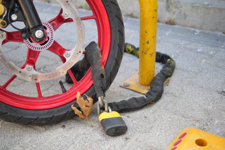 Motorcycle chained to a pole on a city sidewalkの写真素材