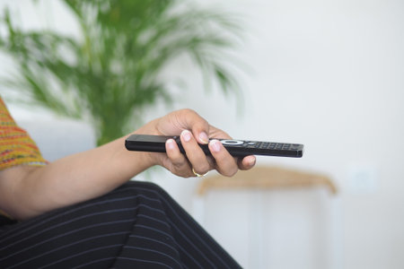 Busy hand holding remote control in a cozy room