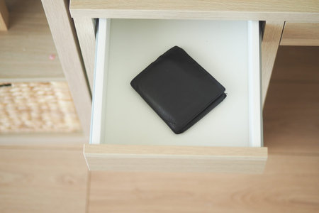 Black wallet resting in an open drawer at home