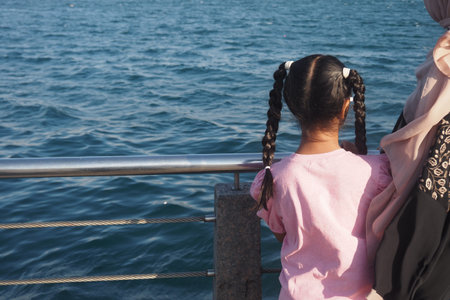 Child enjoying a view of the water with a guardian nearbyの写真素材