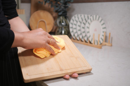 Wiping down a wooden cutting board in a modern kitchen