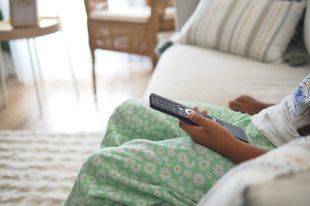 A girl in comfy clothes enjoys a show on TV while sitting on a couch
