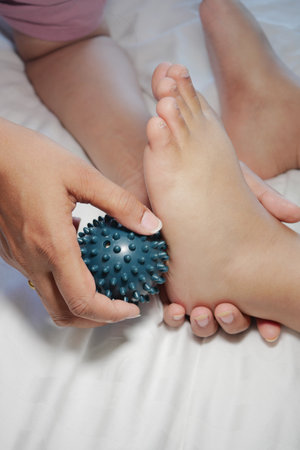 A child enjoys a relaxing foot massage with a spiky ballの写真素材
