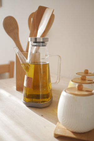 Olive oil dispenser and kitchen utensils on a wooden tableの写真素材