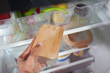 Hand holding a wooden container in a refrigeratorの写真素材