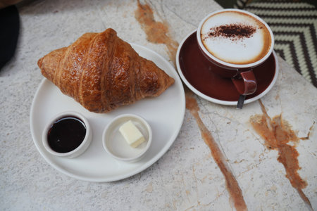 Morning coffee and croissant at a cozy cafeの写真素材