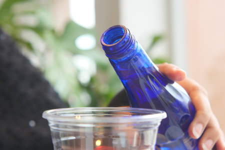 Pouring a blue glass bottle into a clear cup at homeの写真素材