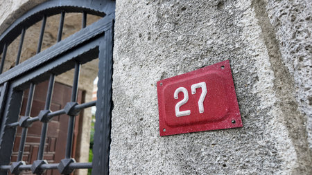 House number 27 on a stone wall with a decorative gateの写真素材