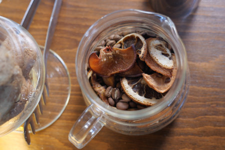 Dried fruits and coffee beans in a glass jar on wooden tableの写真素材