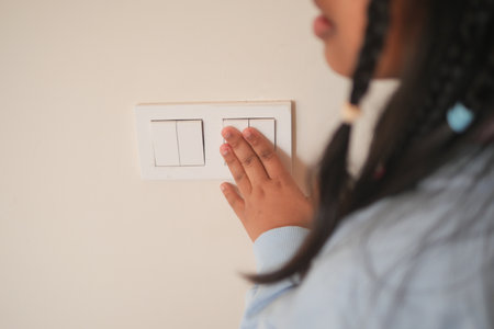 Child reaching for light switch on a wall in homeの写真素材