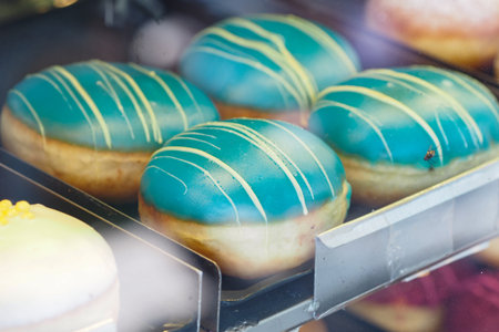 Colorful donuts displayed in a bakery windowの写真素材