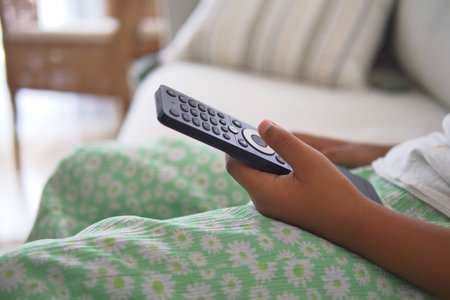 Child relaxing and watching TV with a remote control in hand