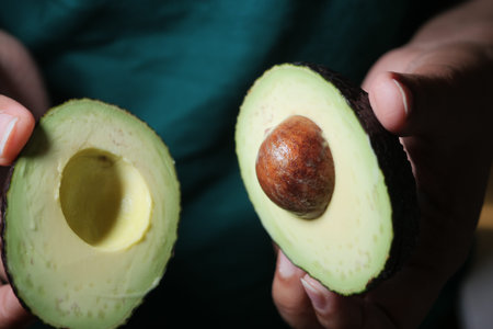 Cut avocado being held by hands in bright light