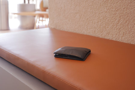 Wallet resting on a brown leather bench in a cafe. lost wallet conceptの写真素材