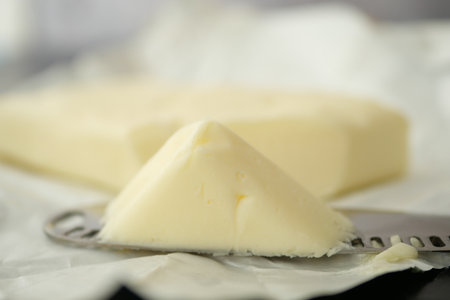 Creamy butter cut from a block on a silver knifeの写真素材