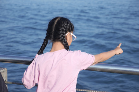 Child enjoying a sunny day by the waterの写真素材