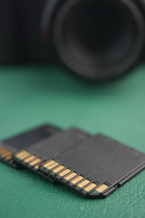 Memory cards lined up on a green surface against a cameraの写真素材