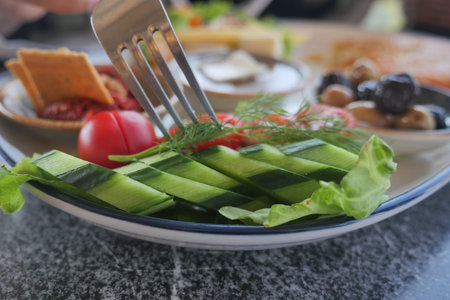 Fresh salad with cucumbers and tomatoes at a sunny cafeの写真素材