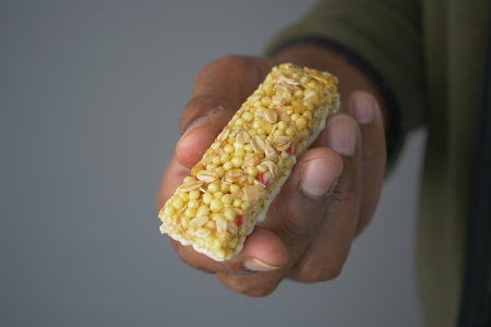 Hand holding a nutritious snack bar made of grainsの写真素材