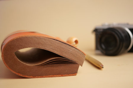 Notebook with leather cover and camera on tableの写真素材
