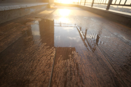 Sunset reflection on a wet wooden surface at a balconyの写真素材