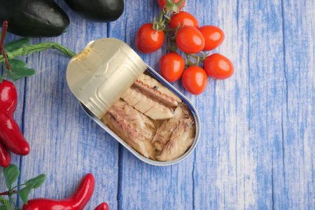 Sardines in tin with vegetables on a wooden tableの写真素材