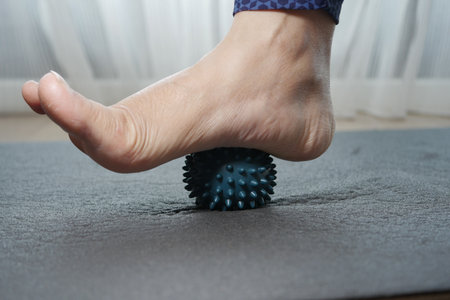 Person using a massage ball on a yoga mat indoorsの写真素材