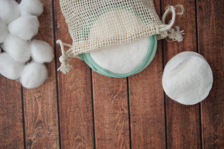 Cotton pads and balls in natural fabric bag on wooden tableの写真素材