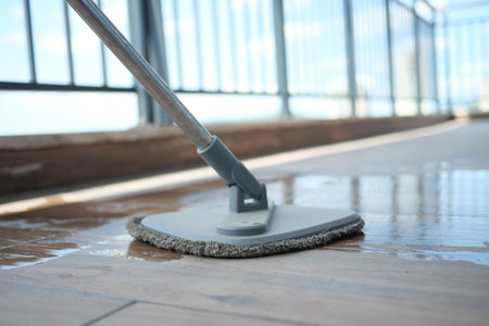 Mop cleaning a wooden floor in bright sunlightの写真素材