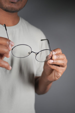 Holding a pair of round glasses in a studio setting