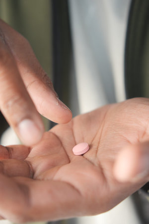 Person holding a pink pill in their hand