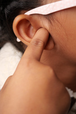 A child is curiously pressing a finger into their ear, exploring sounds