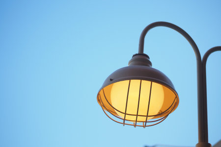 Street lamp glowing against a clear blue skyの写真素材