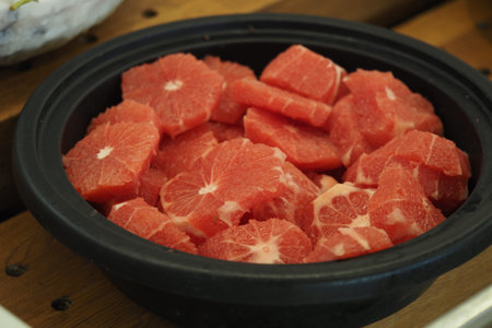 Freshly cut fruit slices in a bowl at a marketの写真素材