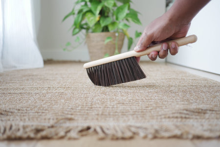 Cleaning a rug with a broom in a bright room
