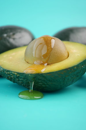 Fresh avocado with honey dripping on a blue surface