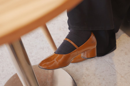 Elegant brown heeled shoe resting under a tableの写真素材