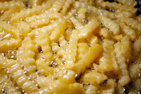 Freshly fried crinkle cut fries sizzling in hot oil