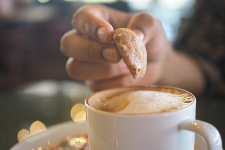Person dipping a cookie into a cup of coffeeの写真素材