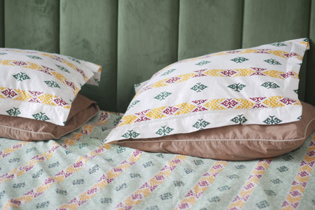 Comfortable bed with colorful patterned pillows and sheets