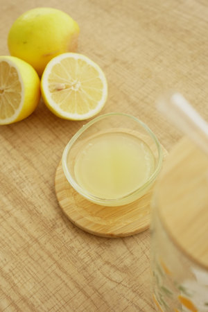 Refreshing lemon juice and fresh lemons on a wooden surfaceの写真素材