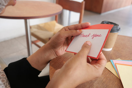 Writing a thank you card in a cozy cafe settingの写真素材