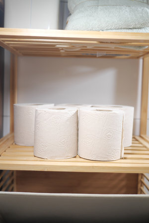 Paper towels neatly arranged on wooden shelf in bathroomの写真素材