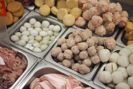 Variety of fresh meats and fish balls displayed in a marketの写真素材