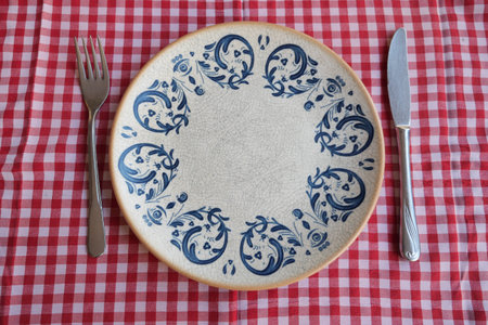 Decorative plate on checkered tablecloth with utensilsの写真素材