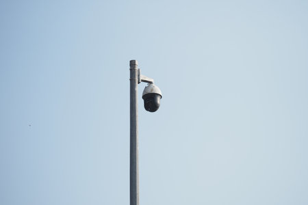 Surveillance camera mounted on a pole in clear skyの写真素材
