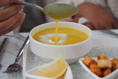 Warm yellow soup served with lemon and croutonsの写真素材