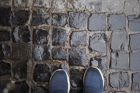 Wet cobblestone street with footwear visibleの写真素材